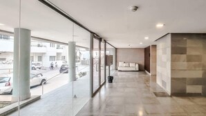 A modern hotel corridor with large windows, a sofa, and a tiled wall. - Ness Tsiyona Cachemire (Tel Aviv)