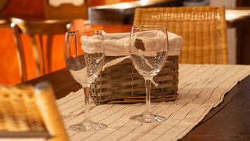 Una mesa de comedor con dos copas de vino y una cesta, sobre un mantel a rayas.
