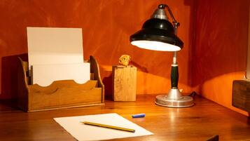 Un bureau en bois avec une lampe de bureau, un crayon, une feuille de papier et une petite boîte en bois contenant une fleur.
