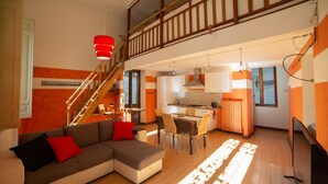 A spacious living area with a large sectional sofa, a dining table, and a kitchen in the background. - Appartamento L'antico Rione (Piazza)