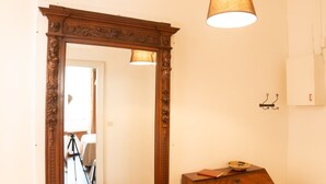 A room with a large ornate mirror, a wooden dresser, and a hanging lamp. - Appartamento L'antico Rione (Piazza)