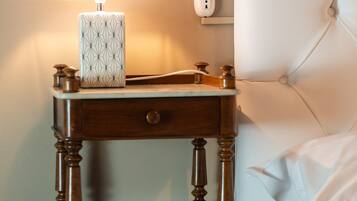 Ein Nachttisch aus Holz mit Lampe und Taschentuchbox neben einem Bett mit einem gepolsterten Kopfteil.