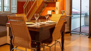 A dining area with a wooden table, wicker chairs, and a staircase in the background. - Appartamento L'antico Rione (Piazza)