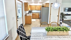 Una cocina compacta con armarios de madera, un refrigerador y un comedor con mesa y sillas.