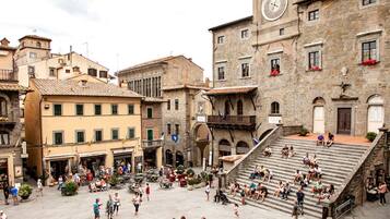 Una piazza vivace con edifici storici, una torre dell'orologio e una scala che conduce a un livello superiore.