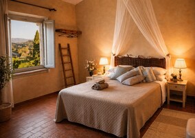 Un dormitorio con una cama grande, una ventana con vistas, una mesita de noche con lámpara y una escalera de madera.