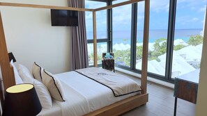 A bedroom with a large window, a bed, a TV, and a nightstand. - Mullet Bay Suites: Your Luxury Stay Awaits (Lowlands)