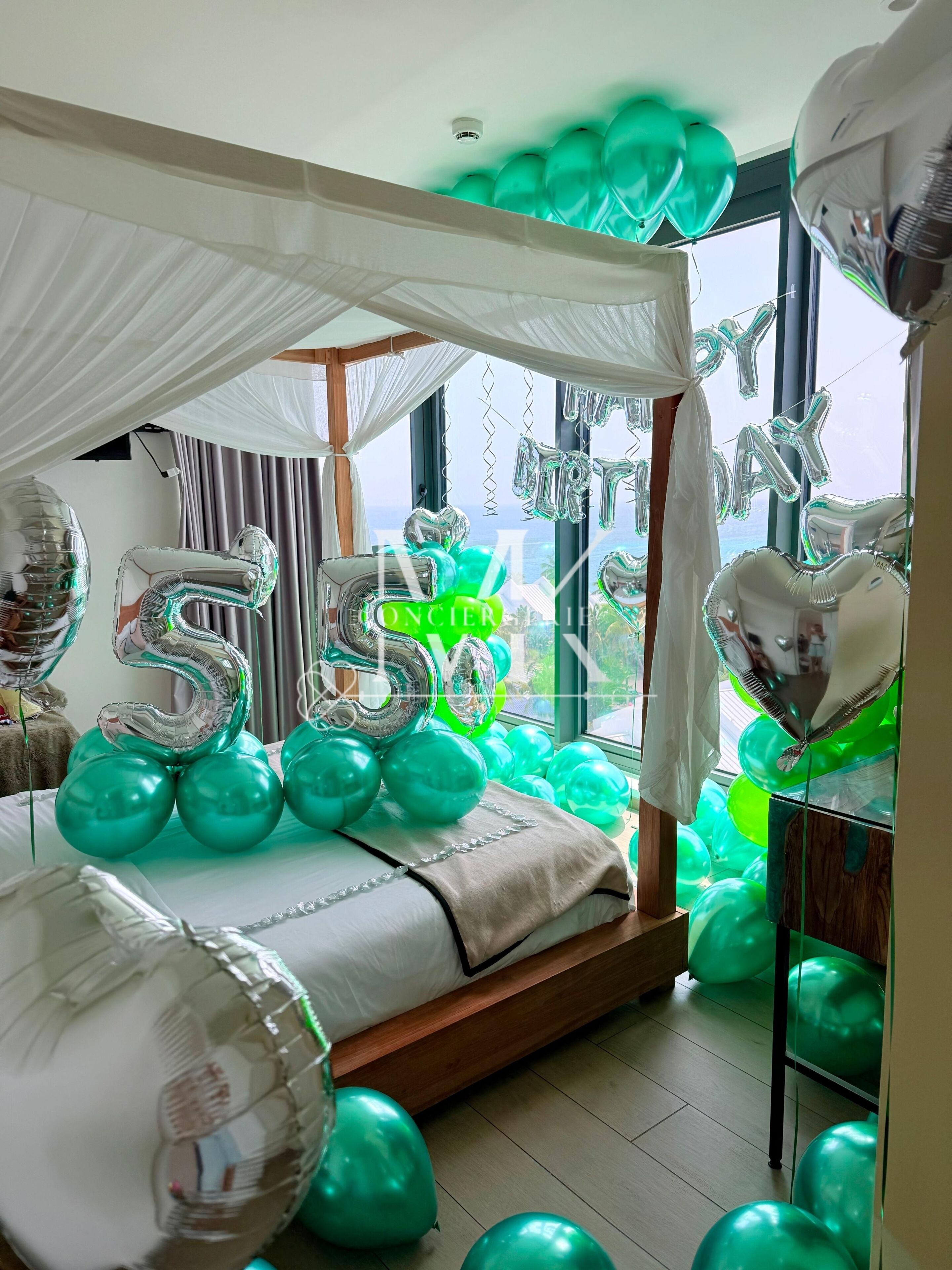 Ein Zimmer mit Baldachinbett, Ballons und Blick durch das Fenster.