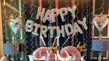 A room with a bed, a mirror, and a wall with a birthday decoration.