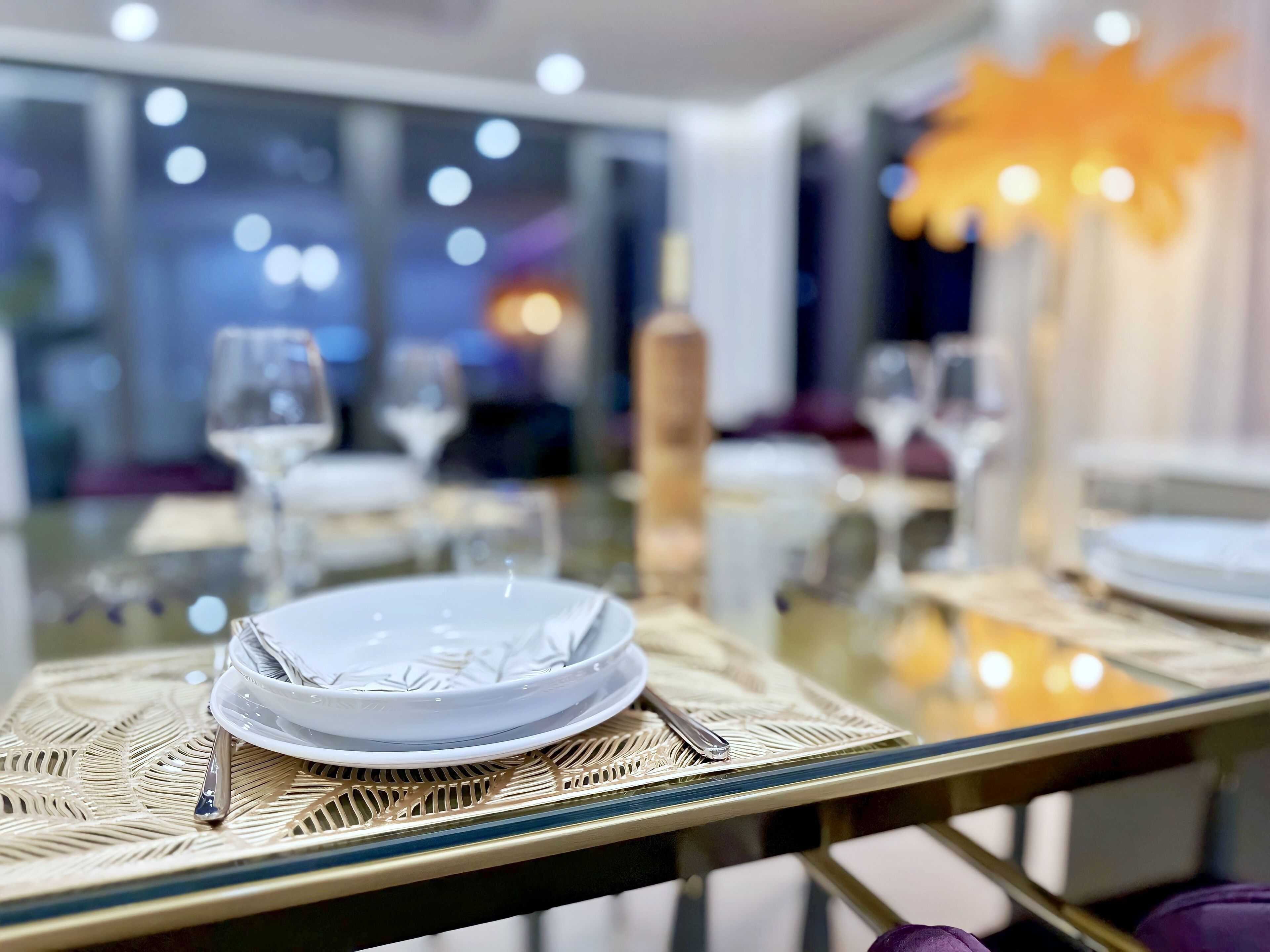 A dining table set with plates, glasses, and cutlery, with a decorative centerpiece.