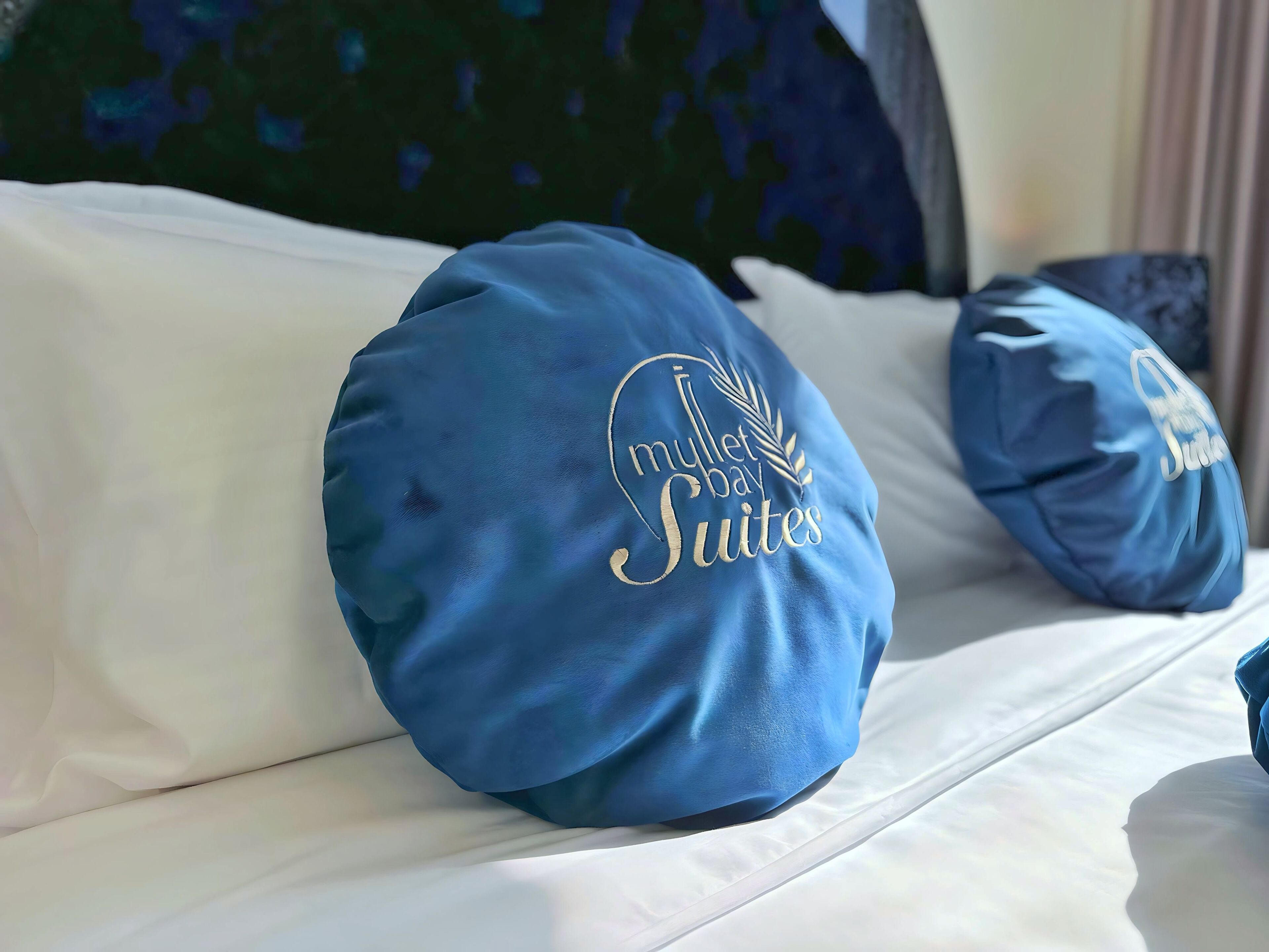 A bed with two pillows, one of which has embroidered text.