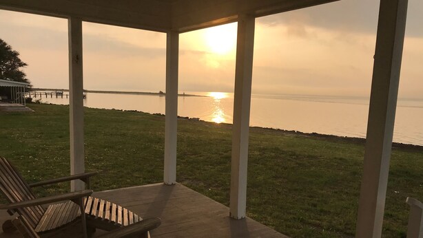 A covered outdoor seating area with a view of a sunset over a body of water. - Down East Waterfront Quaint Farmhouse with Pier Overlooking National Seashore (Atlantic)