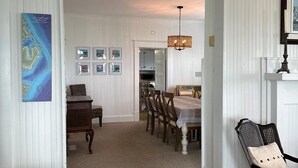 A spacious room with a dining area featuring a chandelier, wooden chairs, and a table. - Down East Waterfront Quaint Farmhouse with Pier Overlooking National Seashore (Atlantic)