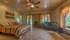 A spacious bedroom with a large bed, a sofa, and a ceiling fan.