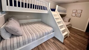 Quarto com beliche, escada e um pequeno espaço para sentar.