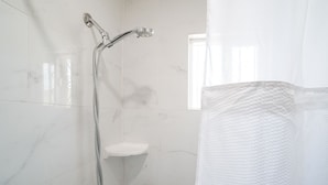 A bathroom with a shower, a sink, and a window.