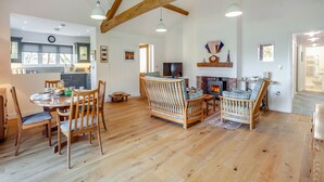 A spacious living area with a fireplace, wooden furniture, and a dining table. - 2 bedroom accommodation in Falfield, near Wotton-under-edge (Falfield, near Wotton-under-edge)