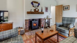 A living room with a fireplace, a television, and two plaid sofas. - 2 bedroom accommodation in Falfield, near Wotton-under-edge (Falfield, near Wotton-under-edge)