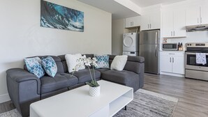 Een moderne woonkamer met een grijze bank, een witte salontafel en een schilderij van een golf.