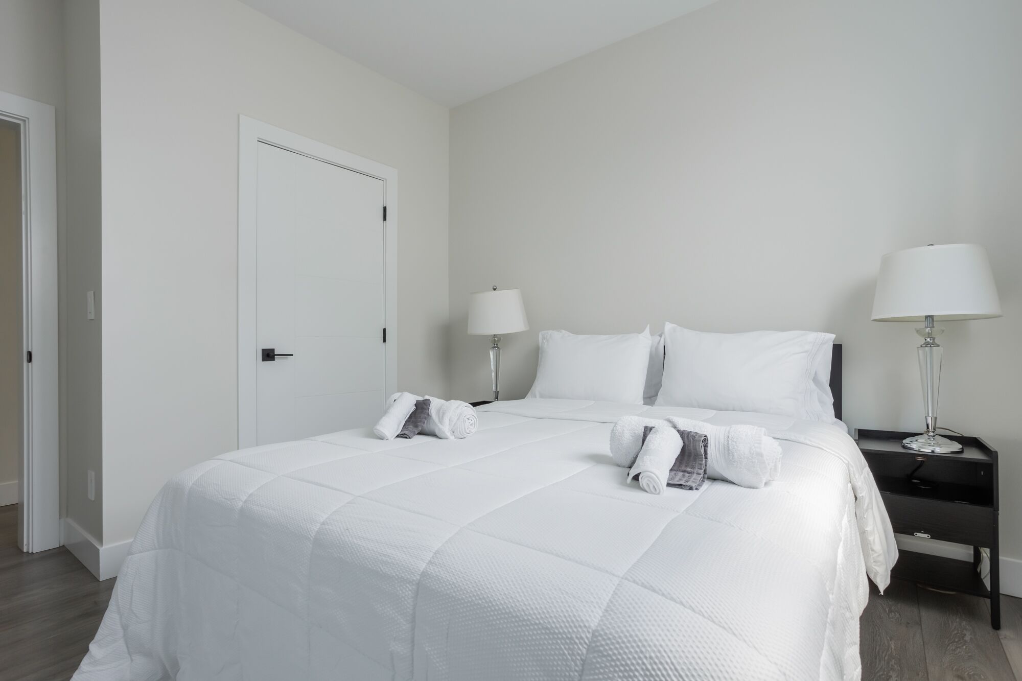Ein Hotelzimmer mit einem großen Bett, zwei Nachttischen und einer Tür.