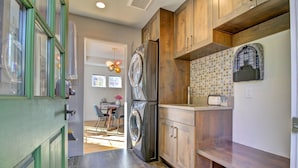 A modern kitchen with wooden cabinets, a built-in washing machine, and a tiled backsplash.