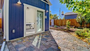 A house with a blue exterior, a glass door entrance, and a stone-paved patio.