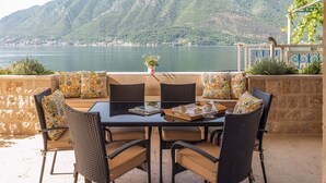 Een terras met een tafel en stoelen, met uitzicht op een meer en bergen.
