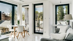 A modern apartment with a dining area, a sofa, and large windows offering views of the outside. - Luxury Apt • Balcony View • 5 min to Downtown (Kraków)