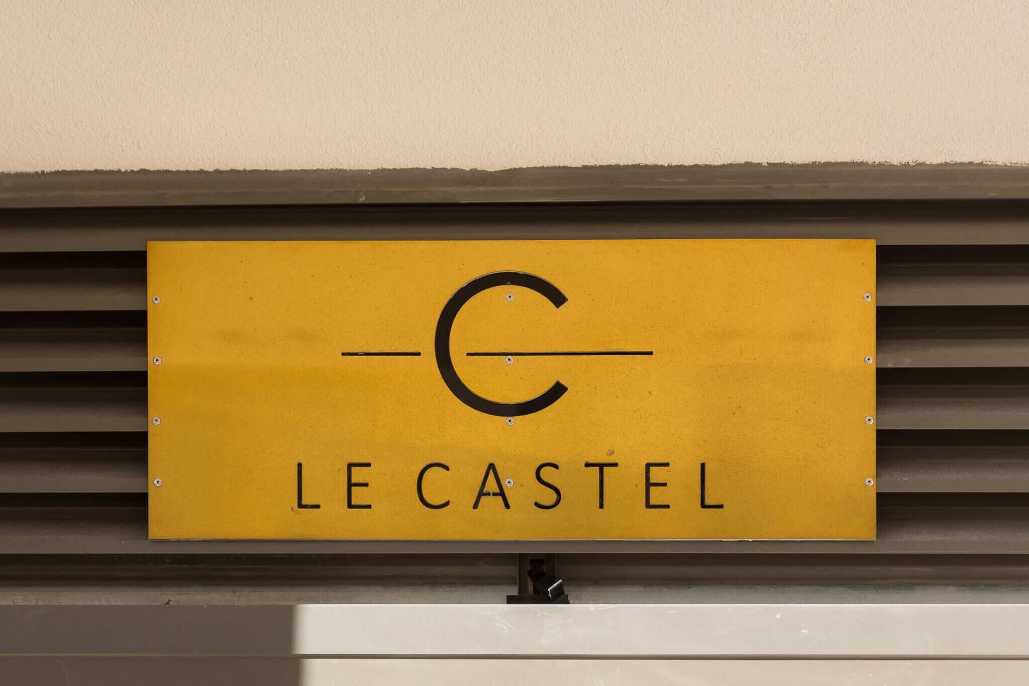 A yellow sign with the text "LE CASTEL" and a stylized 'C' logo.