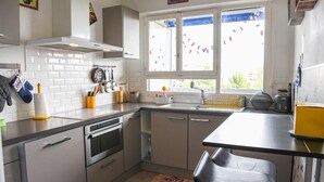 Eine moderne Küche mit weißen Fliesen, Edelstahlgeräten und einem Fenster mit Blick.