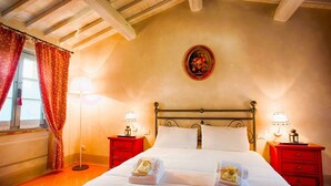 Une chambre d’hôtel avec un grand lit, deux tables de chevet avec des lampes, un rideau rouge et une assiette décorative accrochée au mur.