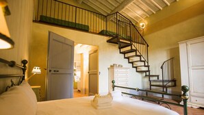 A bedroom with a bed, a staircase, a wardrobe, and a door leading to another room. - Farmhouse San Pietro apartment Fern (Castiglion Fibocchi)