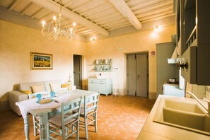 A cozy kitchen with a dining table, chairs, a chandelier, and a tiled floor. - Agriturismo San Pietro Appartamento Fiordaliso (Castiglion Fibocchi)