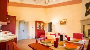 Un coin repas avec une table en bois dressée pour quatre personnes, un buffet rouge et un tableau accroché au mur.