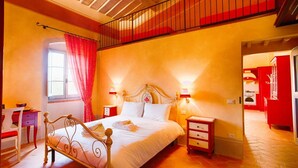 Une chambre à coucher avec un lit, des tables de chevet, un bureau et une fenêtre avec des rideaux.