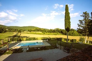 A swimming pool with a view of a vineyard and hills.