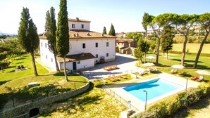 Eine Villa mit Swimmingpool, umgeben von Garten und Bäumen.