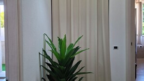 A hallway with a potted plant, a hanging light fixture, and a door leading to another room. - Holiday Home Dolia Center (Dolianova)