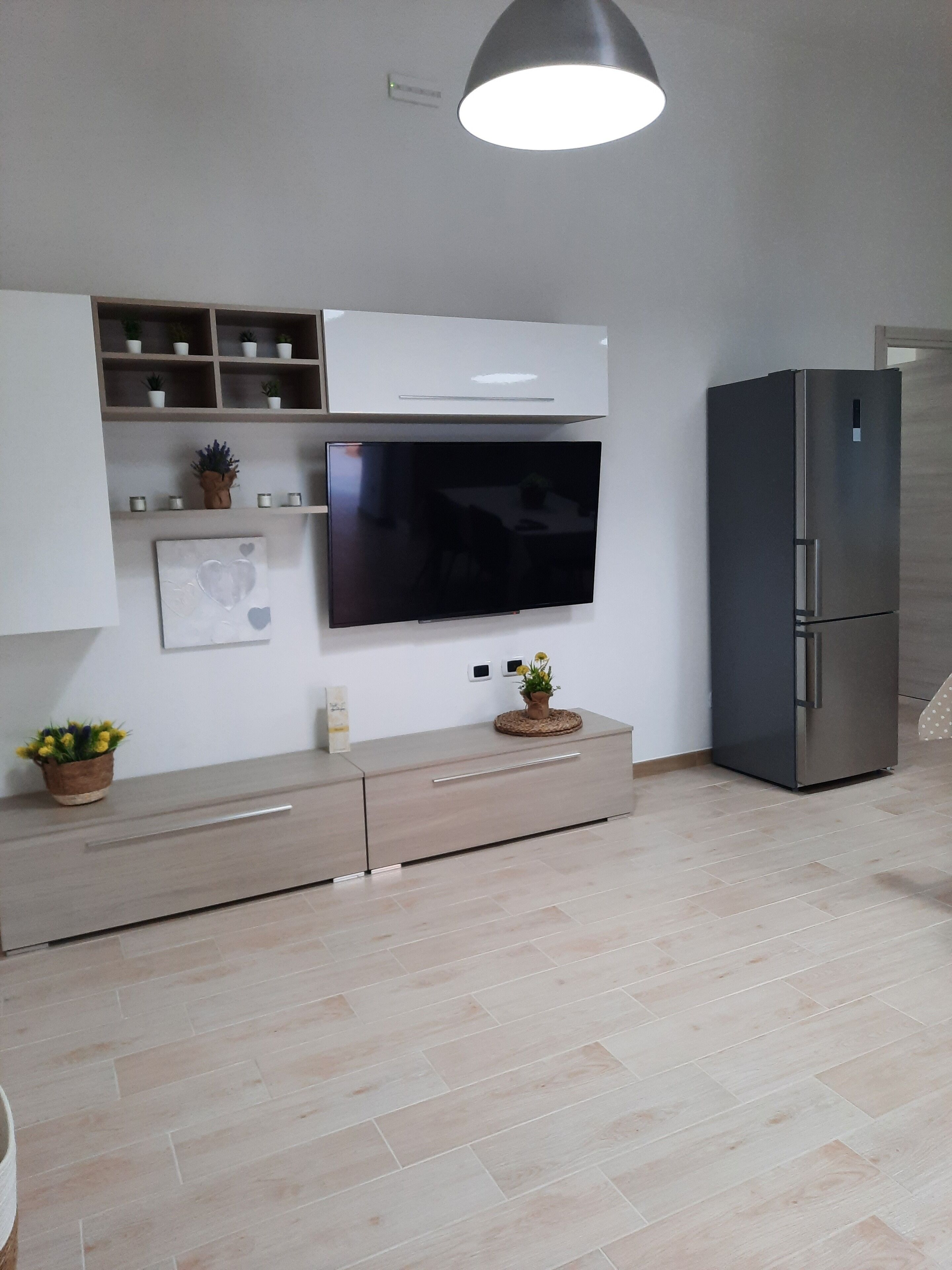 A modern kitchen with a built-in TV, a refrigerator, and a light fixture.