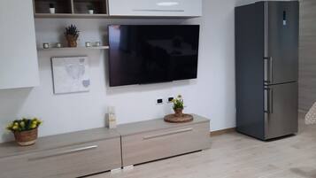 A modern kitchen with a built-in TV, a refrigerator, and a light fixture.
