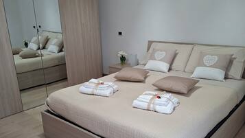 A modern bedroom with a large bed, a wardrobe, and a mirror.