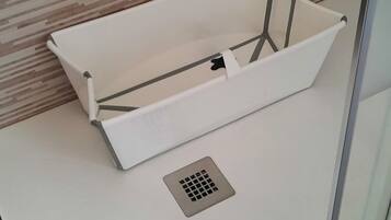 A shower area with a glass door, a white towel, and a showerhead.