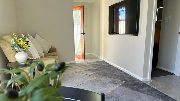 A living room with a sofa, a coffee table, and a plant. There is a door leading to another room. - Sydney Blue mountain Retreat (Kingswood)