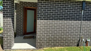 A building with a brick exterior, a wooden door, and a small porch area. - Sydney Blue mountain Retreat (Kingswood)
