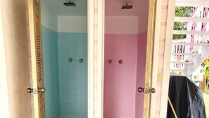 Due bagni con porte, uno con arredamento blu e l'altro con arredamento rosa, e un cappotto nero appeso a destra.