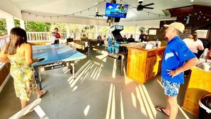 Un'area esterna coperta con tavolo da ping pong, angolo bar e schermo televisivo.