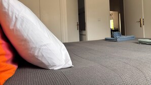 Une chambre à coucher avec un lit, un oreiller blanc, une serviette pliée et une armoire.