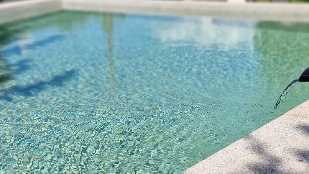 Une piscine à eau claire, avec un niveau d’eau visible et un robinet situé sur le côté droit.