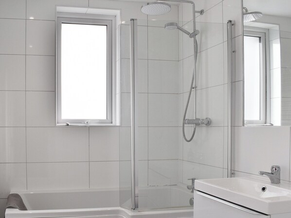 A modern bathroom with a glass-enclosed shower, a large window, and a white sink.
