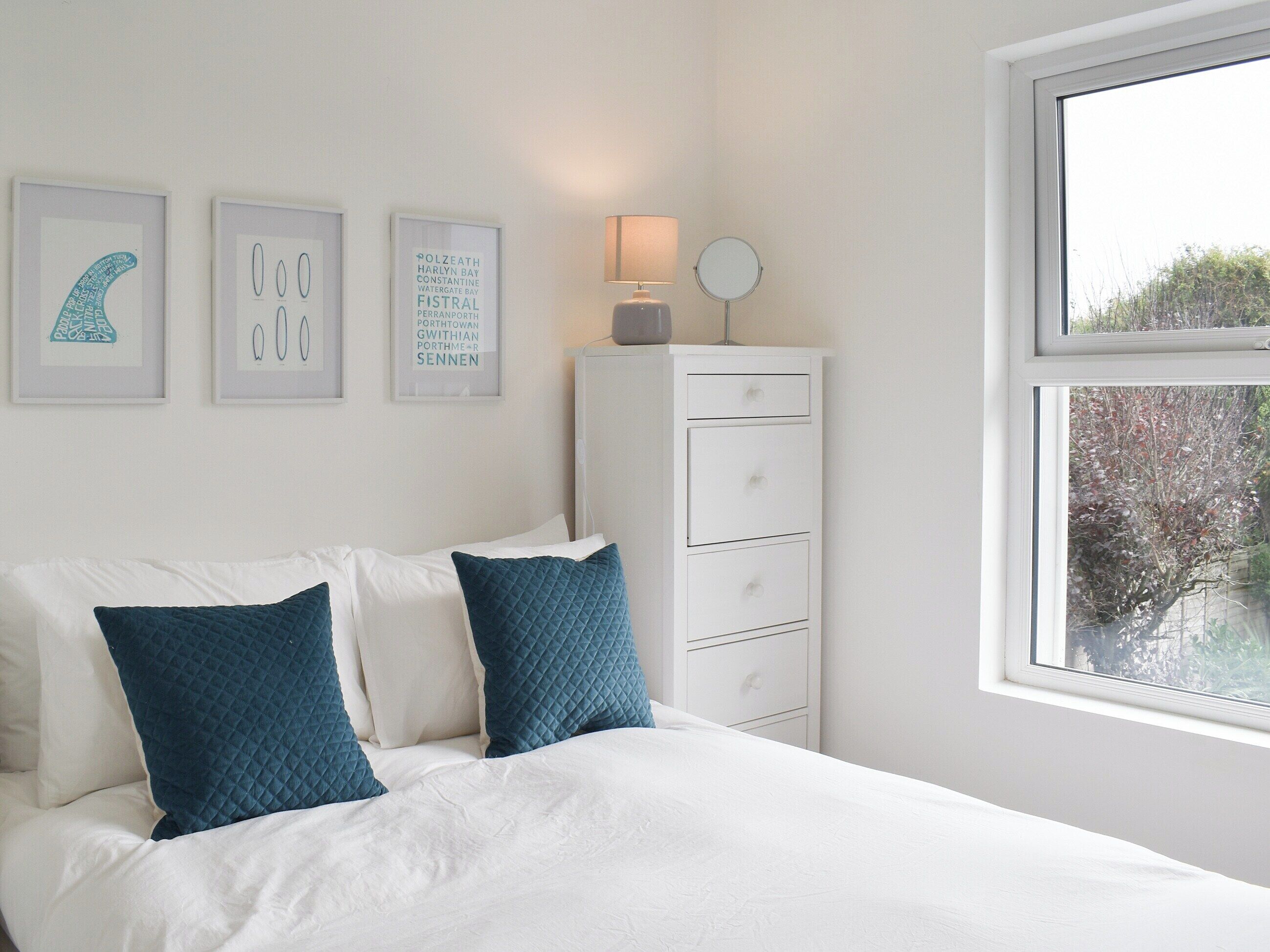 A bedroom with a bed, white dresser, and framed pictures on the wall.